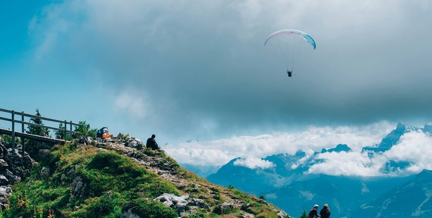 A breathtaking aerial view of a person enjoying Paragliding in the clear blue skies.