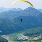 A mesmerising view of people paragliding above lush green mountains during the day.