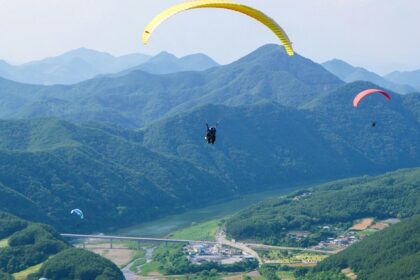 A mesmerising view of people paragliding above lush green mountains during the day.