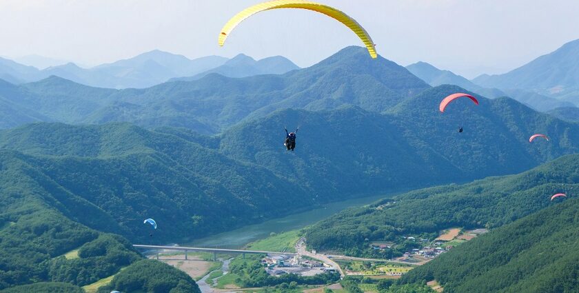 A mesmerising view of people paragliding above lush green mountains during the day.