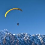 A glimpse of a person gliding high up in the clear skies and soaking panoramic vistas.