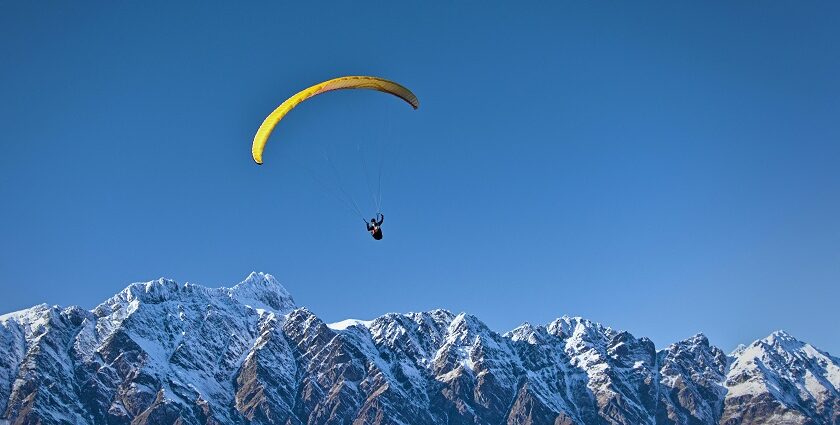 A glimpse of a person gliding high up in the clear skies and soaking panoramic vistas.