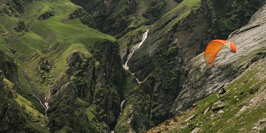 Paragliding in the mountains, with breathtaking aerial views of rugged peaks.