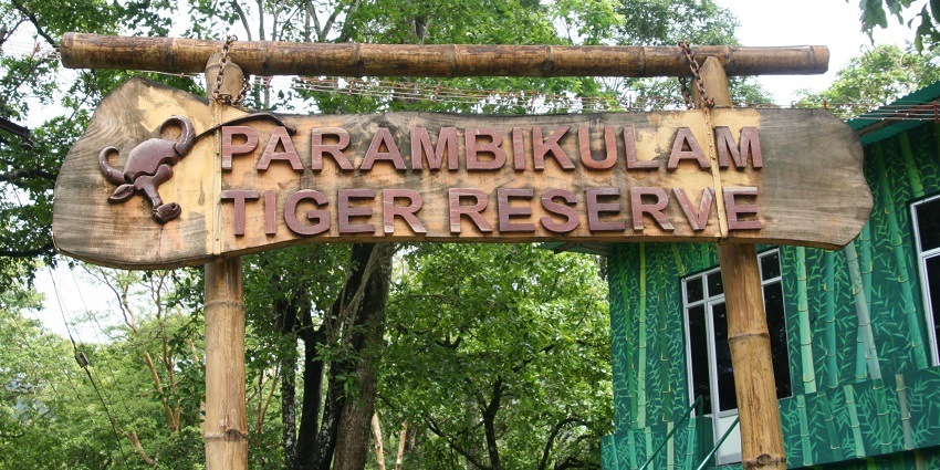 A frontal view of a board saying Parambikulam Tiger Reserve in bold letters in red.