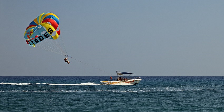 Scenic snapshot of a man parasailing over the blue ocean with the help of a boat