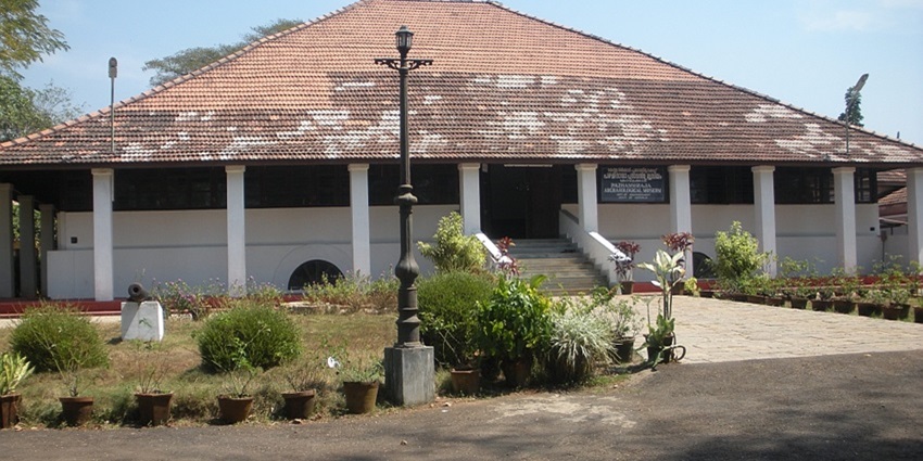 A frontal view of the Pazhassiraja Museum in Kozhikode with a green lawn in front.