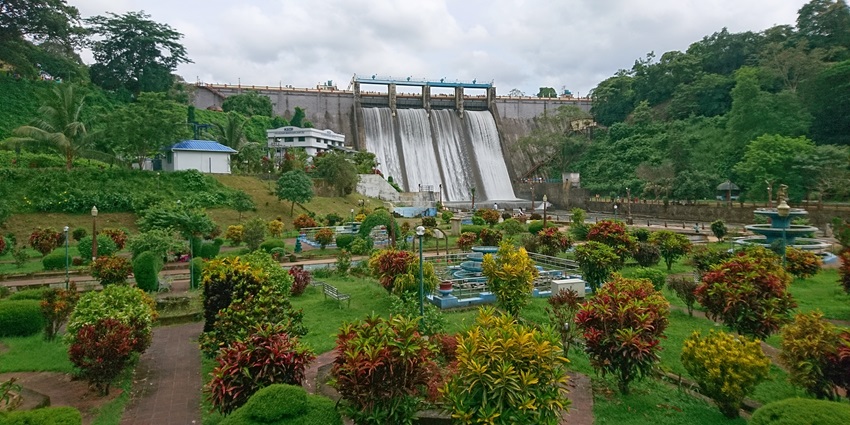 A picture of a stunning dam located behind a beautiful garden with various flowers blooming