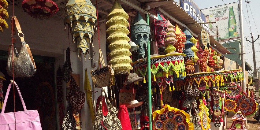 A view of a street market with colourful local handicrafts displayed during the daytime.