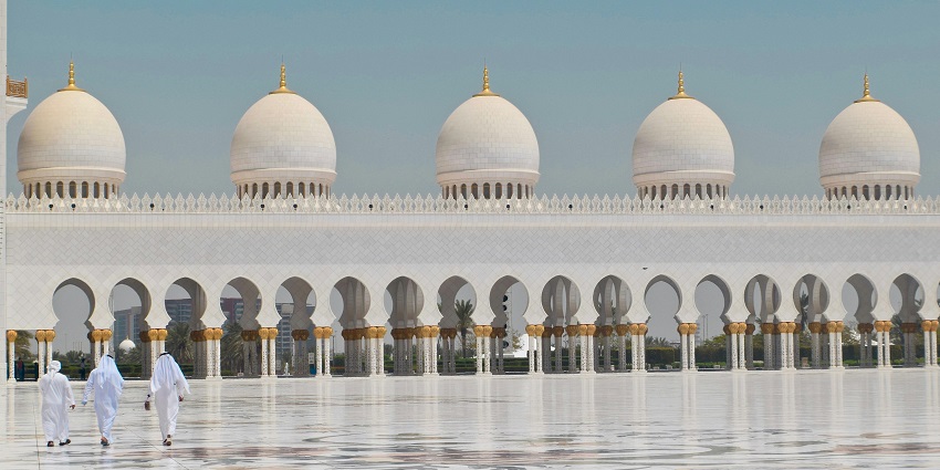 A picture of three men walking in the premises of a mosque, a holy place of worship.