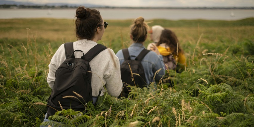 Girls walking through green grass - pack your essentials for Badarpur Fort tour.