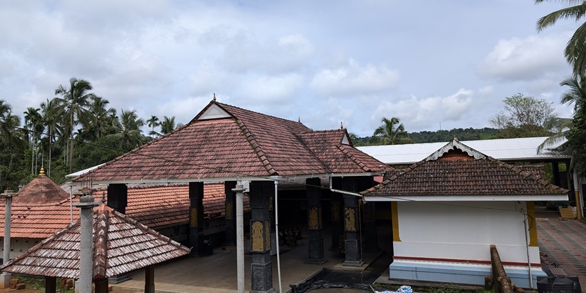 A picture of a traditional Hindu temple with intricate carvings and a garden area
