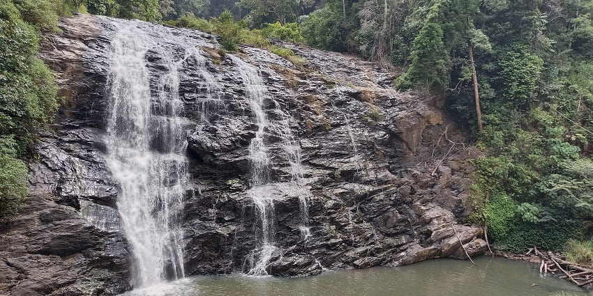 A picture of a waterfall, with water cascading down a hill into a scenic river