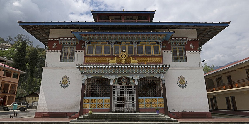 A frontal view of a monastery in Sikkim with traditional white exteriors and intricate art decorating the outside walls hu