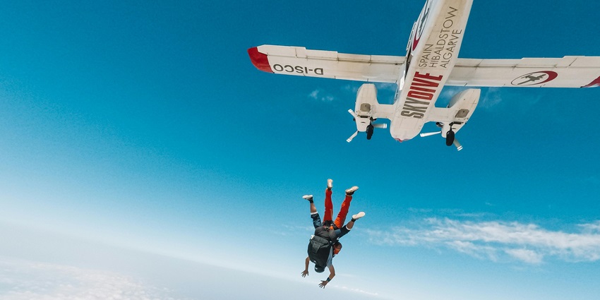 Photography of a plane with skydivers leaping out, showcasing the moment of exit.