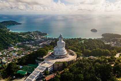 An image of a light sky and blue ocean behind the big Buddha Statue in Phuket, Thailand.