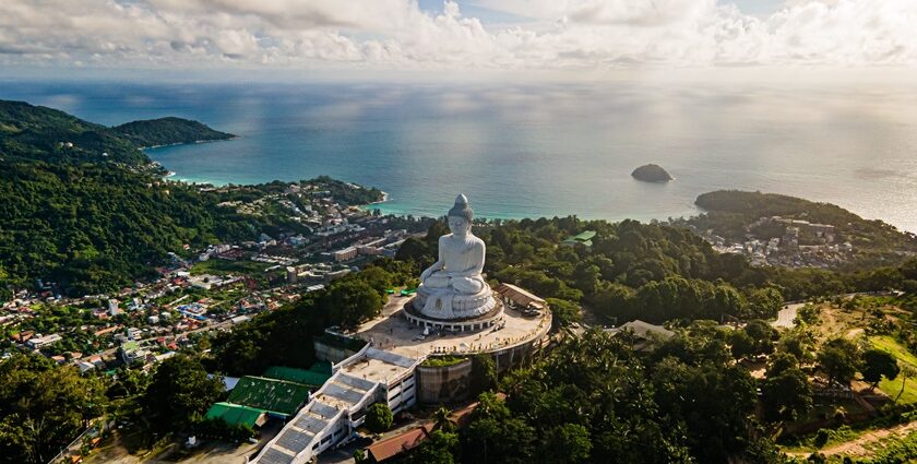 An image of a light sky and blue ocean behind the big Buddha Statue in Phuket, Thailand.