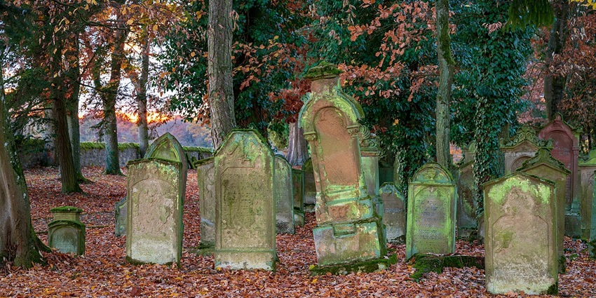 Autumn sunset over a haunted cemetery’s eastern wall and historic gravestones.