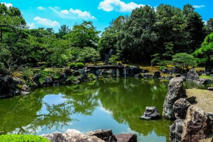 A scenic view of a park covered with verdant grasses, lush green trees, and flowers.