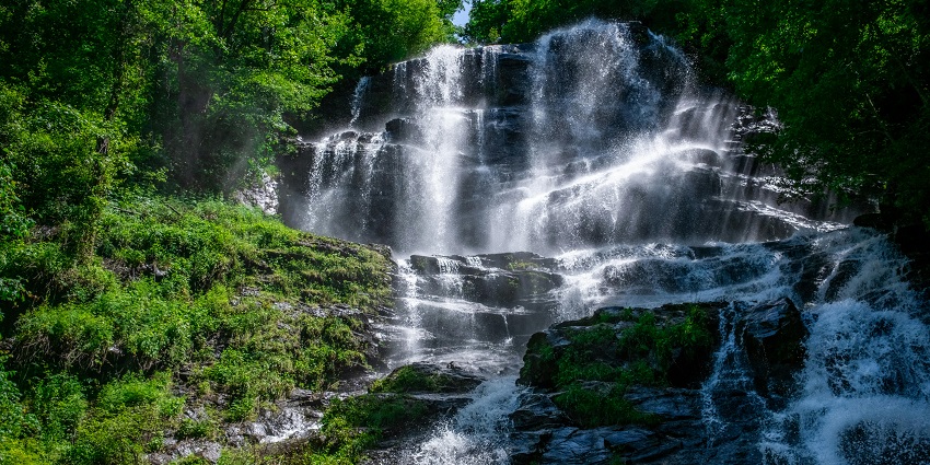 Picture of a beautiful waterfall descending on a rock bed in the scenic forest.