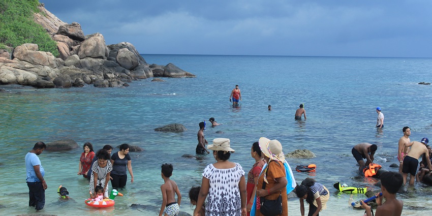 Rocky island with dense greenery surrounded by clear blue waters, known as Pigeon Island.