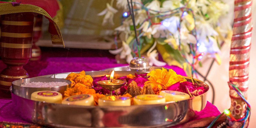 Image of a pooja thali decorated with flowers, incense stick and other hindu ritual essentials