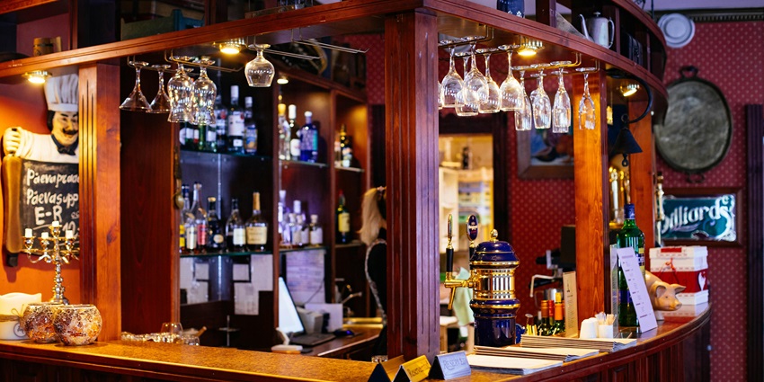 A bar counter with numerous beverages and glasses in the background