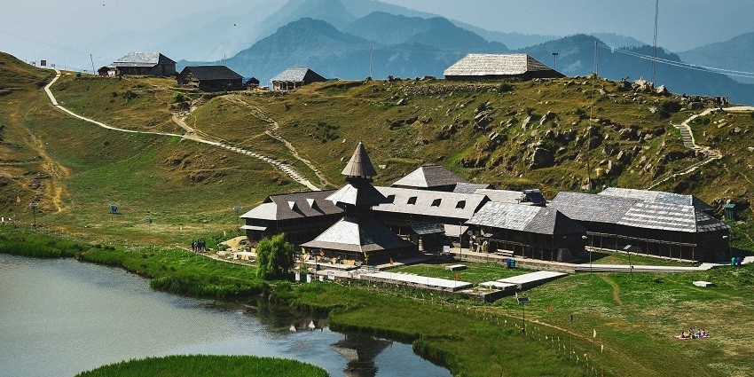 A scenic glimpse of shimmering waters surrounded by a small village near Prashar Lake.
