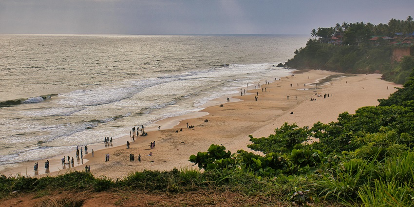 Crowds of beachgoers enjoying a sunny summer day by the turquoise sea and golden sand.
