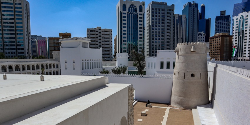 A picture of a museum in Abu Dhabi taken in a way that the tall skyscrapers are visible