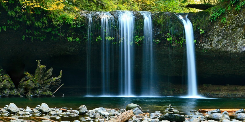 A panoramic view of water descending from the top and merging with a calm river.