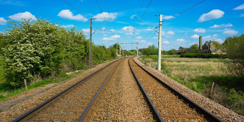 Scenic view of railroads winding through lush green countryside under a clear blue sky.