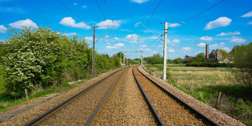 Railway track cutting through lush green surroundings, creating a picturesque landscape.