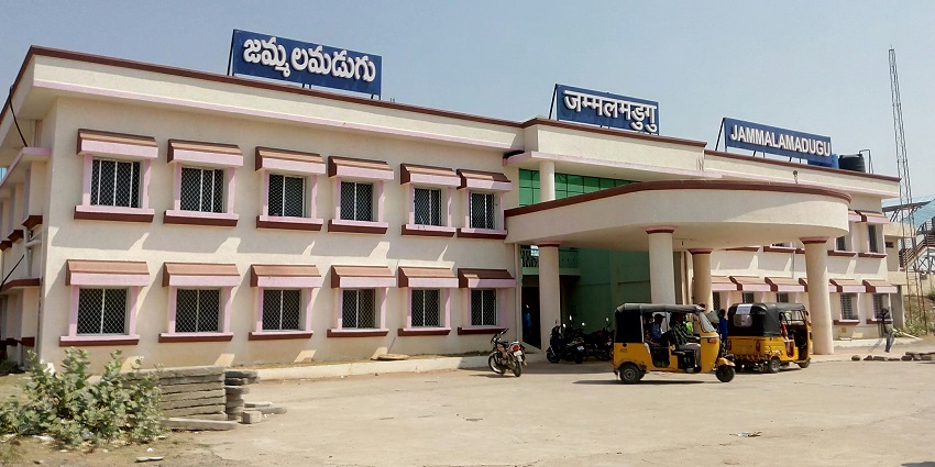 Entrance of Jammalamadugu railway station with a sign and surrounding greenery.
