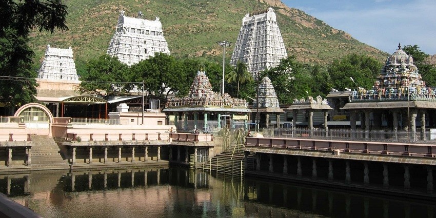 View of a place of worship with lush green mountains and clear sky in the background.