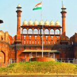 A frontal view of the Red Fort in Delhi with a garden in front