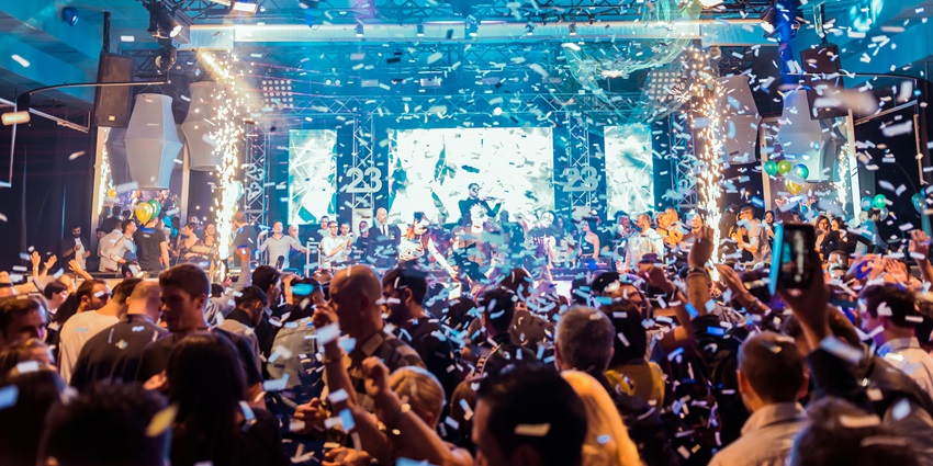 Crowd of people partying under vibrant blue and green stage lights.