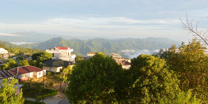 A morning view of Reiek with a backdrop of mountains with lush greenery and cloudy sky.