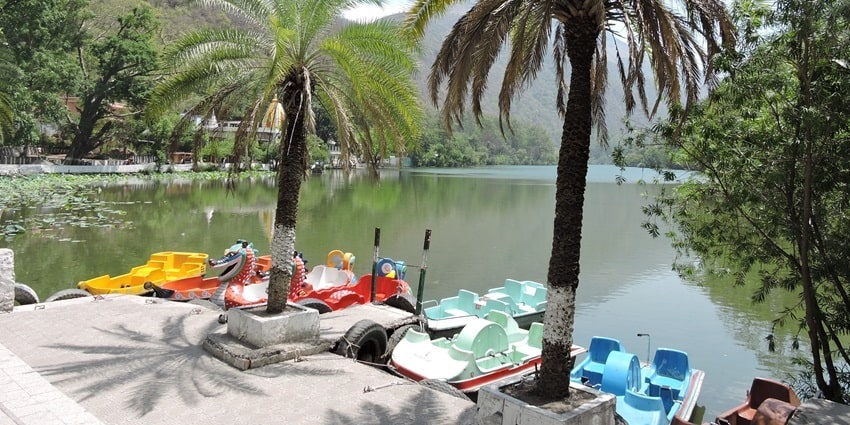 Serene Renuka Lake in Himachal Pradesh, surrounded by lush greenery and mountains.