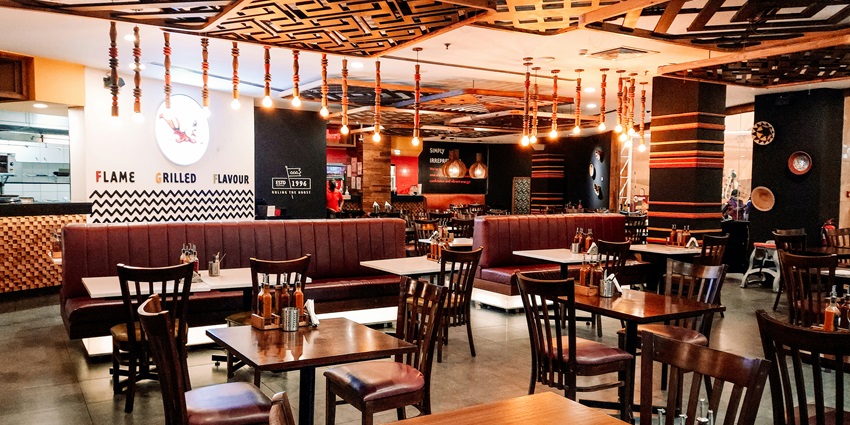 View of the inside of a restaurant with wooden tables and chairs in Kochi, Kerala