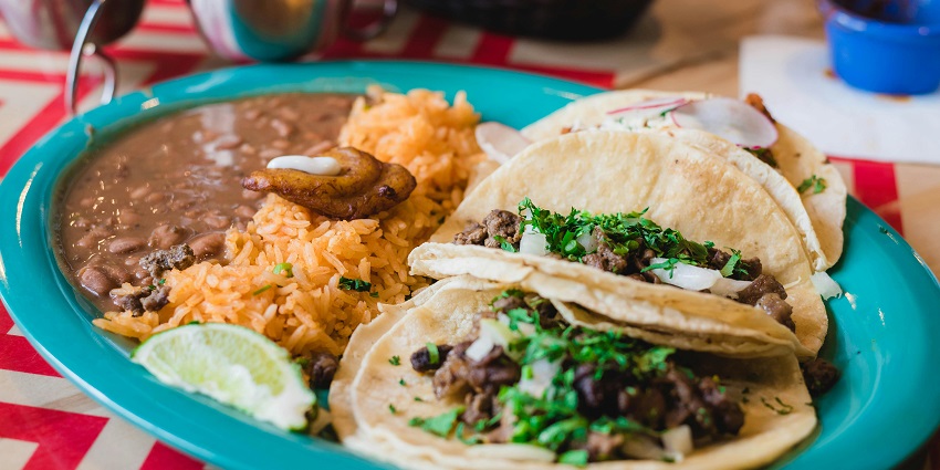Close-up picture of delectable tacos and rice on a plate with kidney beans curry.