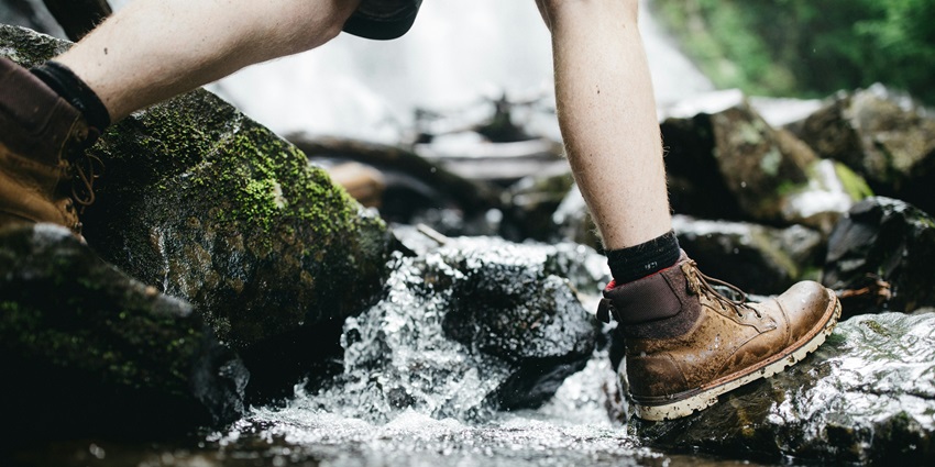 A person crossing a gushing river, an adventure activity to try in Solang Valley in April.