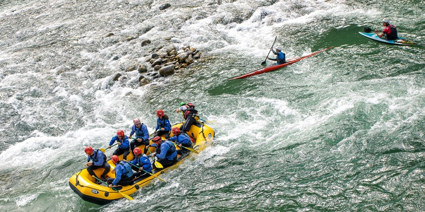 Aerial view of the group of people enjoying the river rafting amidst lush forest