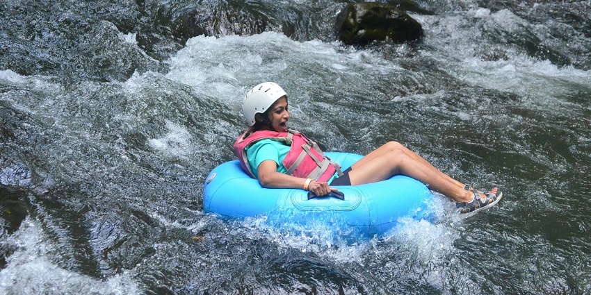 A woman floating through a river on an inflated rubber tube with protection gear on