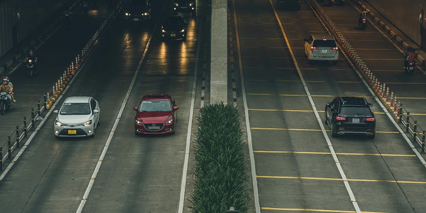  Nighttime highway scene with cars driving, illuminated by streetlights and city lights.