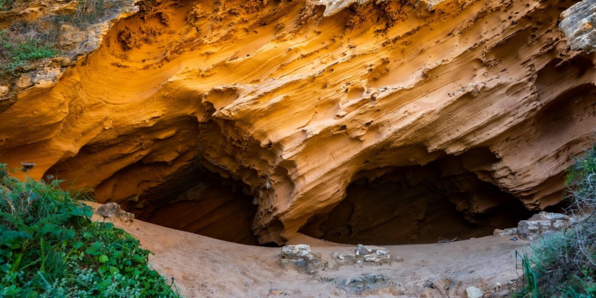 A cave entrance surrounded by rugged terrain, showcasing natural stone formations.