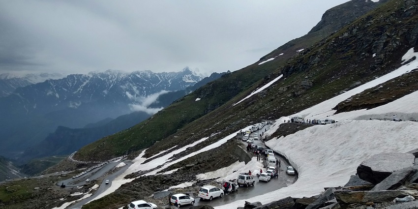 A breathtaking view of a snow-covered mountain range with a narrow strip of road.