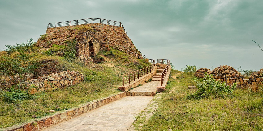 Image of ancient ruins of a fort on top of the hill, surrounded by lush greenery.