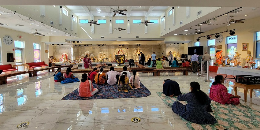 A picture of the interiors of a Sai Baba temple in Dubai with devotees sitting and praying