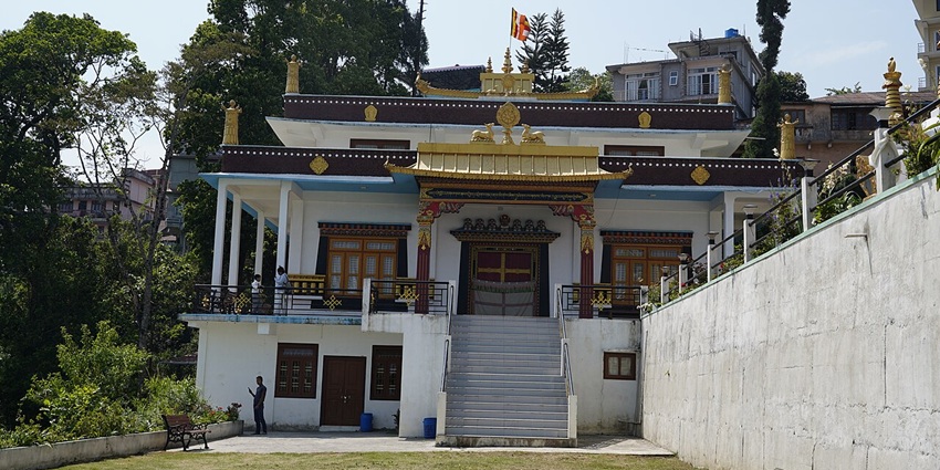 A frontal view of a traditional monastery near Ravangla with white exteriors and a garden area in front