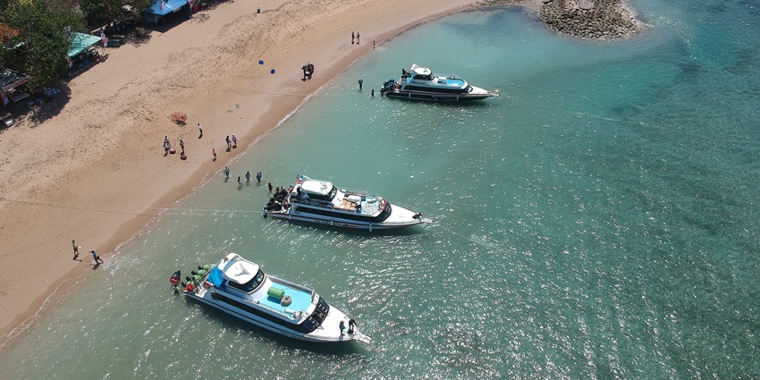 A breathtaking aerial view of a turquoise water body with 3 speed boats during the day.